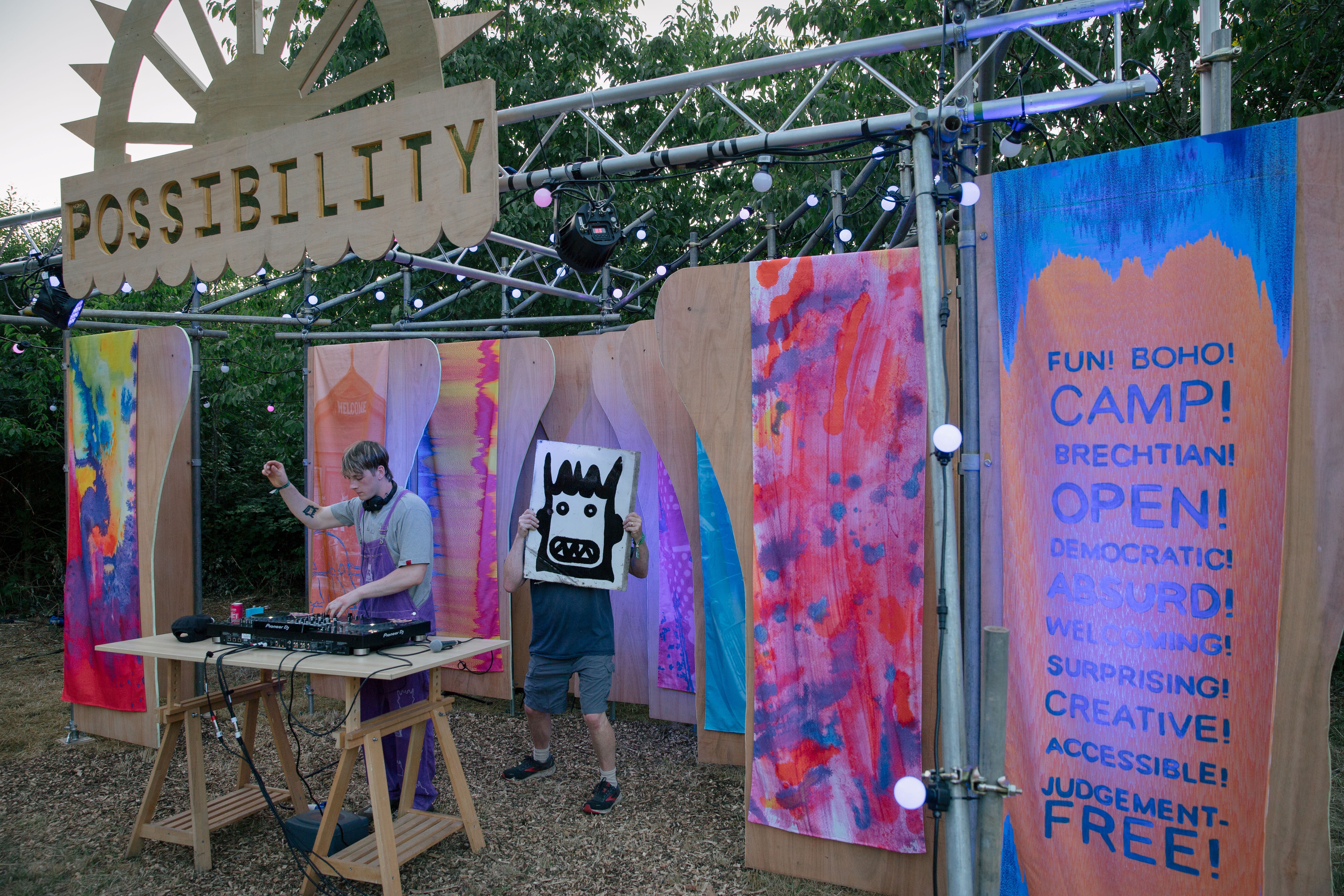A DJ plays music on a colourful stage
