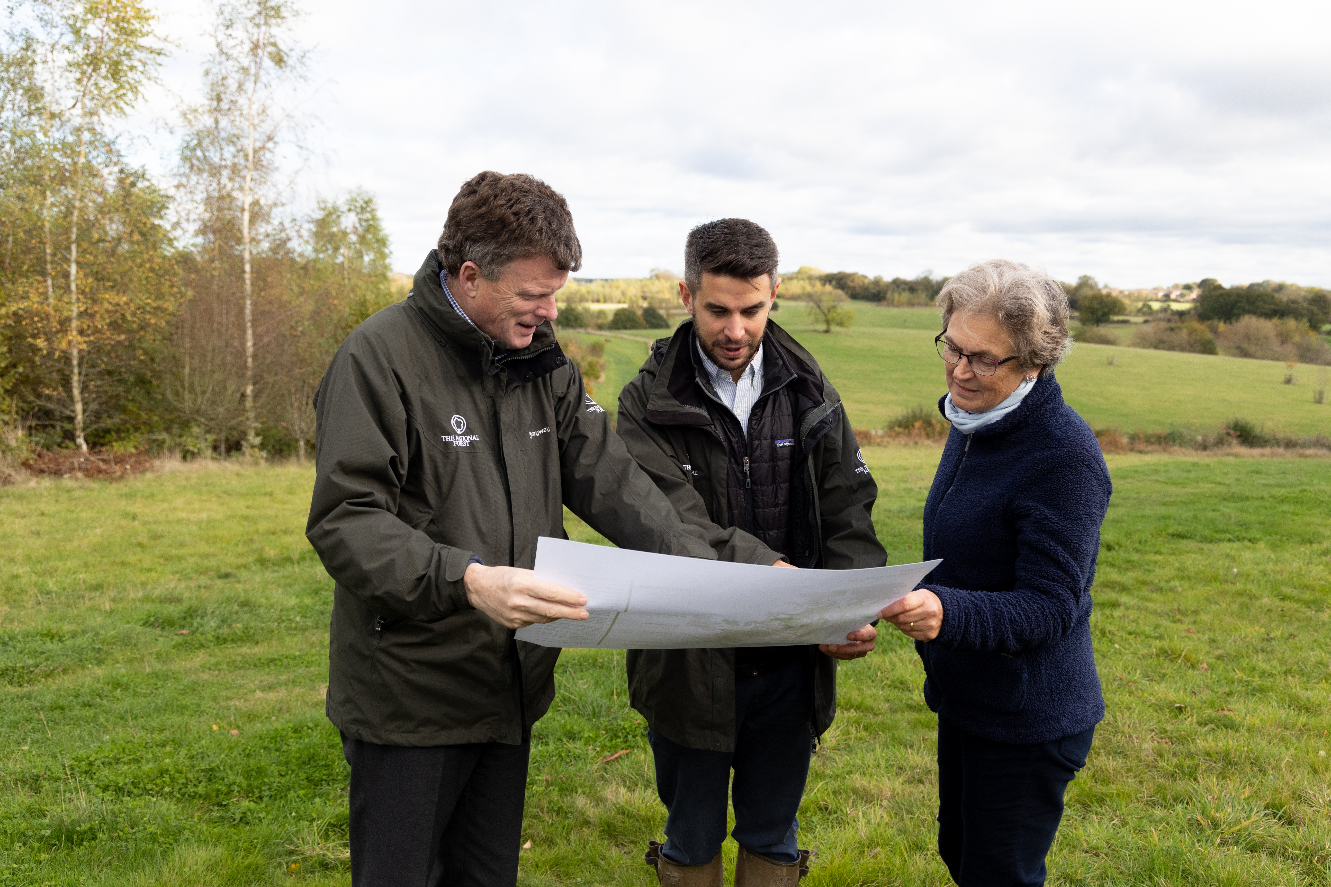 Three people look at a map